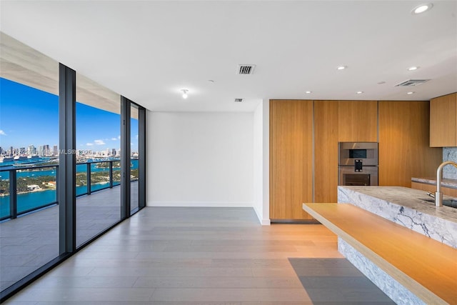 kitchen with double oven, sink, hardwood / wood-style floors, and expansive windows