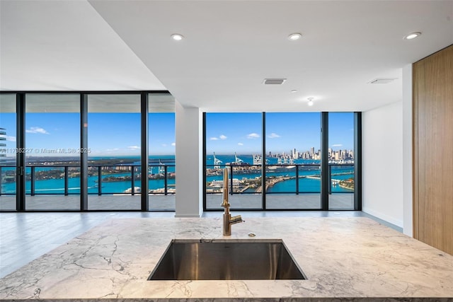 kitchen featuring expansive windows, a water view, sink, and plenty of natural light