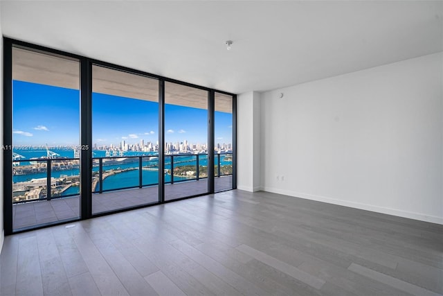 spare room with a water view, expansive windows, and hardwood / wood-style floors