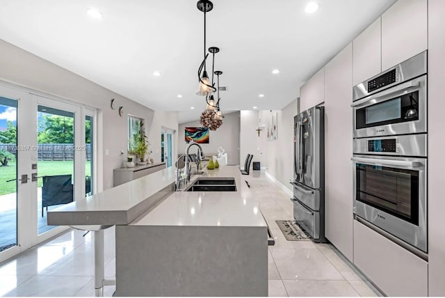 kitchen with sink, appliances with stainless steel finishes, white cabinets, decorative light fixtures, and french doors