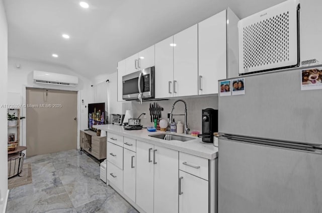 kitchen featuring sink, white cabinetry, vaulted ceiling, an AC wall unit, and stainless steel appliances