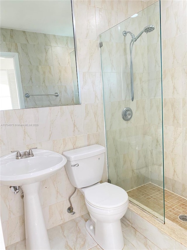 bathroom featuring toilet, sink, tile walls, and a tile shower