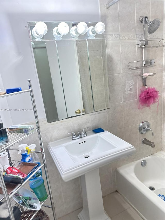 bathroom with tiled shower / bath combo, sink, tile walls, and decorative backsplash