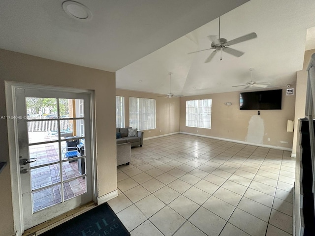 unfurnished living room with vaulted ceiling, plenty of natural light, and light tile patterned floors