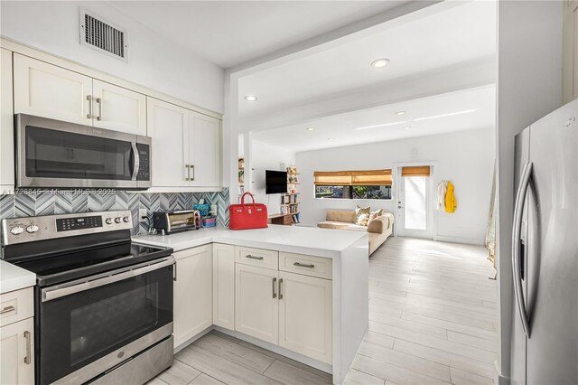 kitchen featuring white cabinetry, sink, kitchen peninsula, and appliances with stainless steel finishes