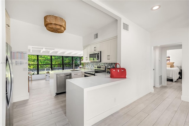 kitchen featuring stainless steel appliances, tasteful backsplash, visible vents, and a peninsula