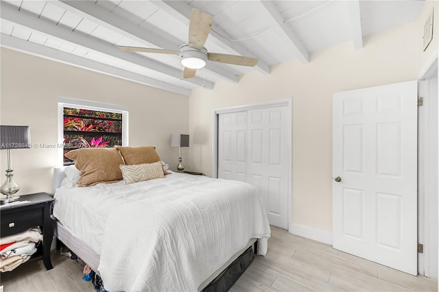 bedroom featuring baseboards, lofted ceiling with beams, light wood-style flooring, a closet, and a ceiling fan