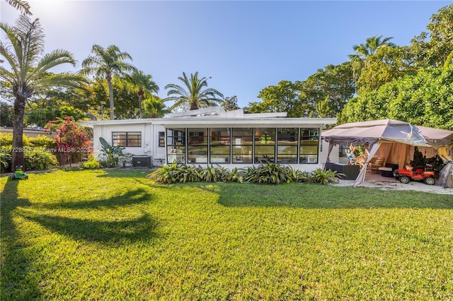 back of house featuring a patio, a yard, and a sunroom