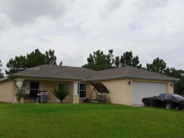 single story home featuring an attached garage, a front yard, and stucco siding