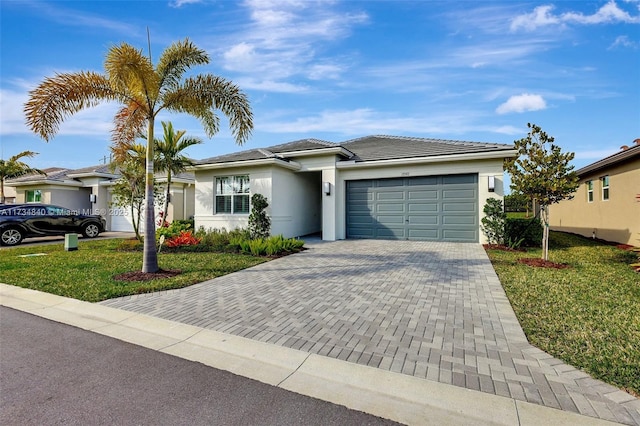 view of front of property featuring a garage, decorative driveway, a front yard, stucco siding, and a tiled roof