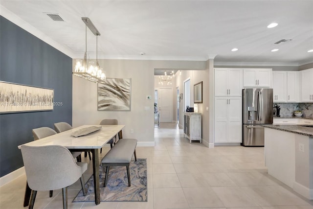 tiled dining space with an inviting chandelier and crown molding