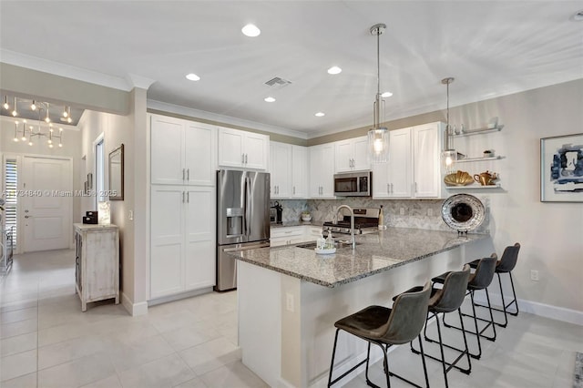 kitchen with appliances with stainless steel finishes, a peninsula, backsplash, a kitchen bar, and baseboards