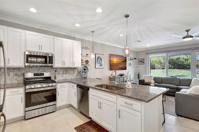 kitchen featuring appliances with stainless steel finishes, a sink, a peninsula, open floor plan, and white cabinets
