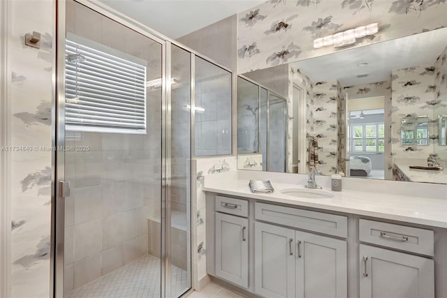 ensuite bathroom featuring wallpapered walls, a shower stall, and vanity