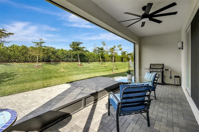 view of patio with ceiling fan, area for grilling, view of scattered trees, and outdoor dining area