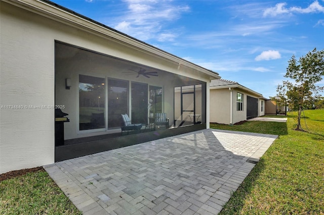rear view of house featuring a patio, a ceiling fan, a lawn, and stucco siding