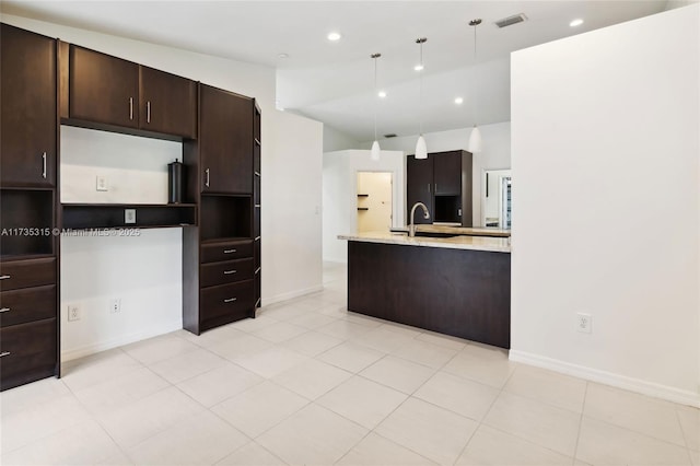 kitchen with dark brown cabinets, light tile patterned floors, paneled built in refrigerator, pendant lighting, and light stone countertops