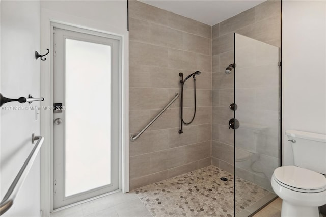 bathroom featuring tiled shower, tile patterned floors, and toilet