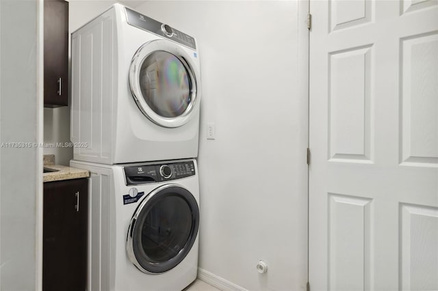 laundry room with cabinets and stacked washer and clothes dryer