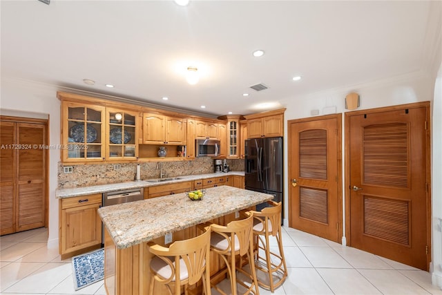 kitchen with light tile patterned flooring, a kitchen bar, sink, a center island, and appliances with stainless steel finishes