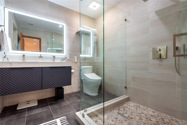 bathroom featuring walk in shower, tile patterned floors, toilet, tile walls, and vanity