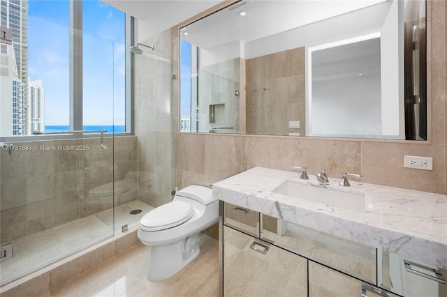 bathroom with a shower with door, tile walls, tile patterned flooring, a water view, and toilet