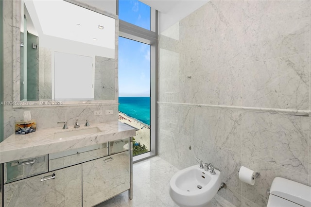 bathroom featuring a water view, a bidet, toilet, and tile walls