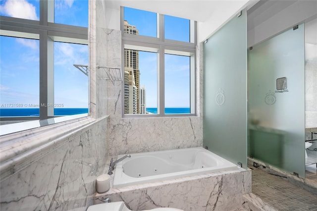 bathroom featuring tiled tub and a water view