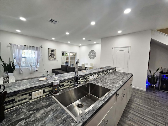 kitchen featuring white cabinetry, dark stone counters, dark wood-type flooring, and sink