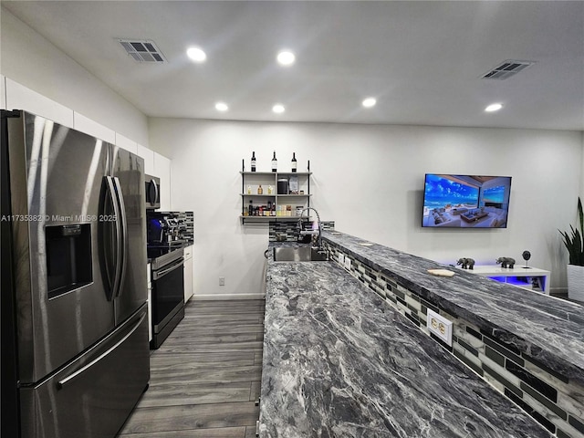 kitchen with appliances with stainless steel finishes, sink, white cabinets, and dark stone counters