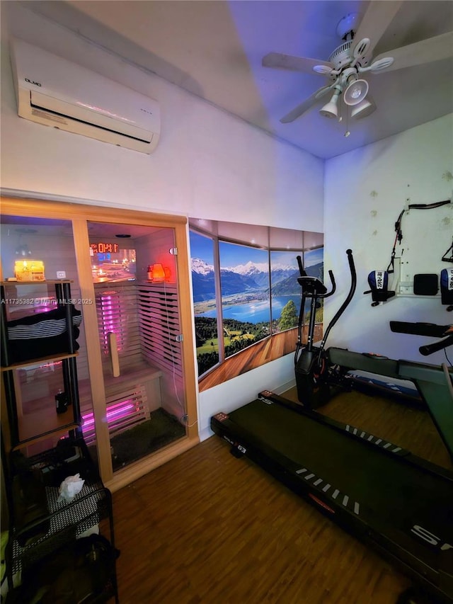 workout room with ceiling fan, wood-type flooring, and a wall mounted AC