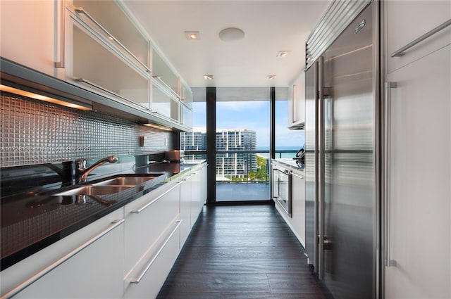 kitchen featuring sink, dark hardwood / wood-style floors, floor to ceiling windows, white cabinets, and built in fridge