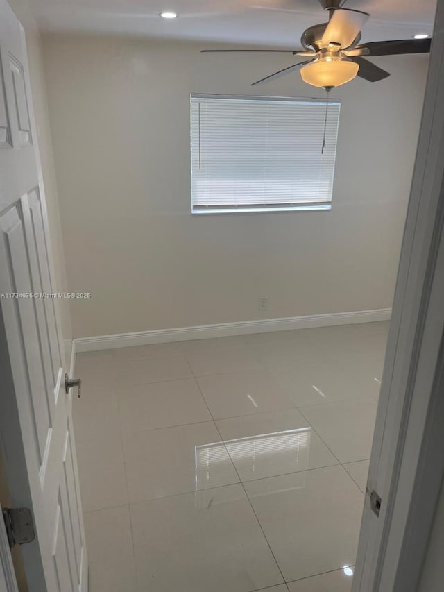 tiled empty room featuring ceiling fan