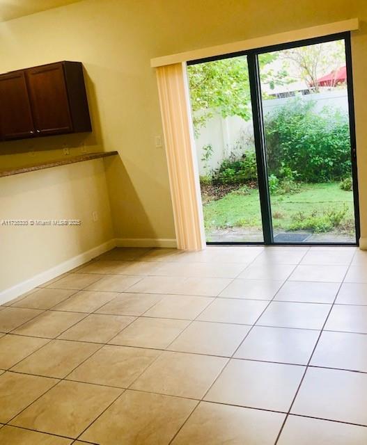 doorway to outside with light tile patterned flooring and plenty of natural light