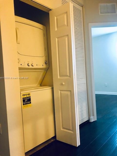 washroom featuring dark wood-type flooring and stacked washer / dryer