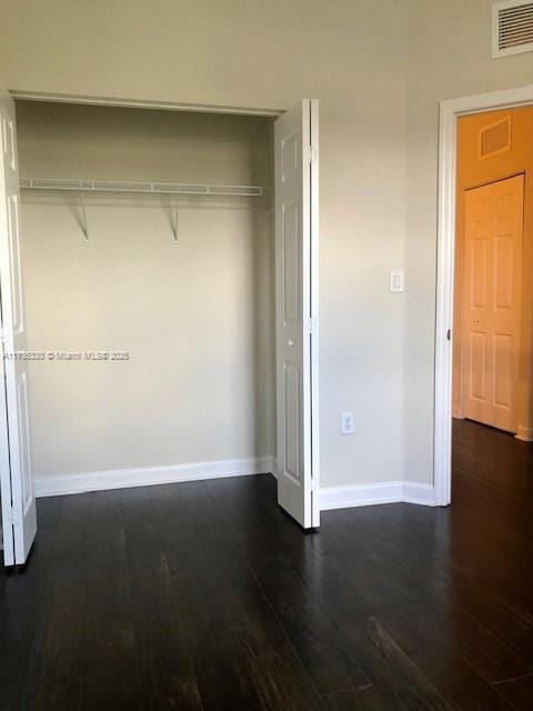 unfurnished bedroom featuring dark hardwood / wood-style floors and a closet