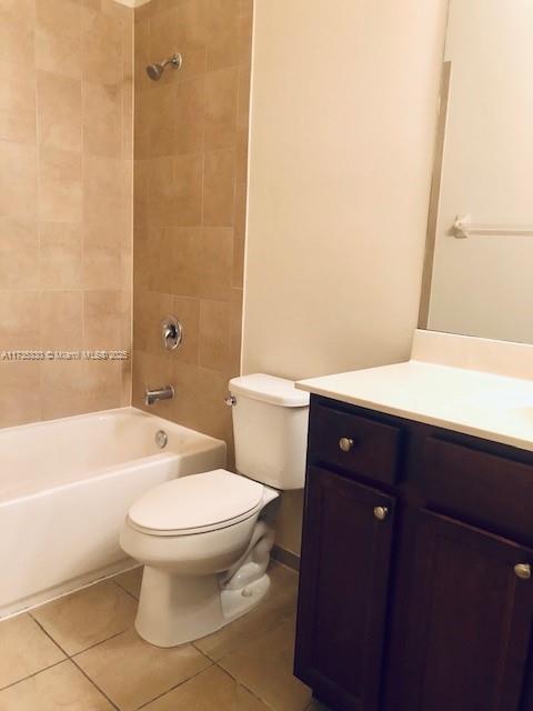 full bathroom featuring tiled shower / bath combo, vanity, tile patterned floors, and toilet