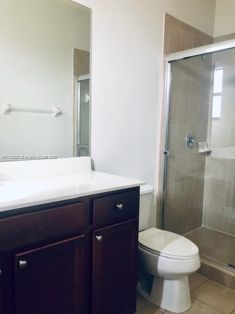 bathroom with tile patterned floors, toilet, a shower with shower door, and vanity