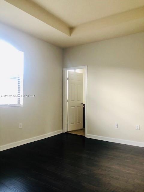 spare room featuring dark hardwood / wood-style floors and a tray ceiling