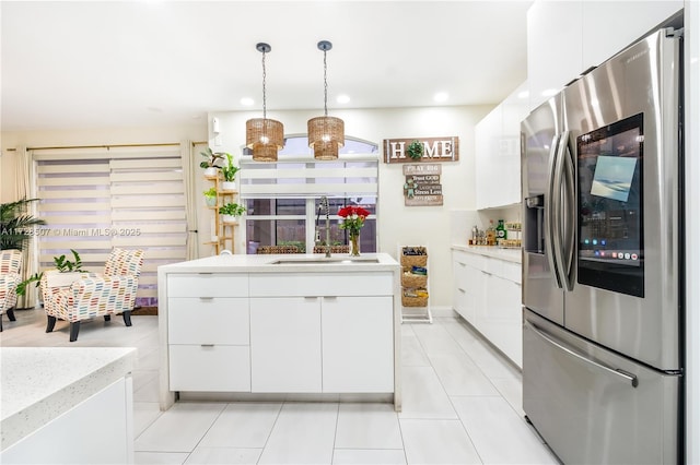 kitchen with decorative light fixtures, white cabinetry, sink, stainless steel fridge, and light tile patterned floors