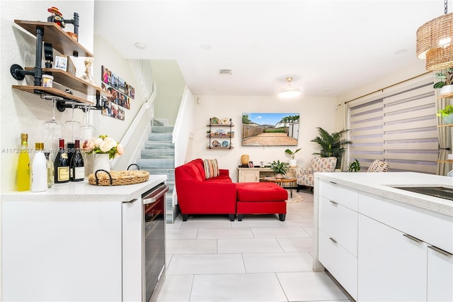 interior space featuring white cabinetry, sink, light tile patterned floors, and beverage cooler