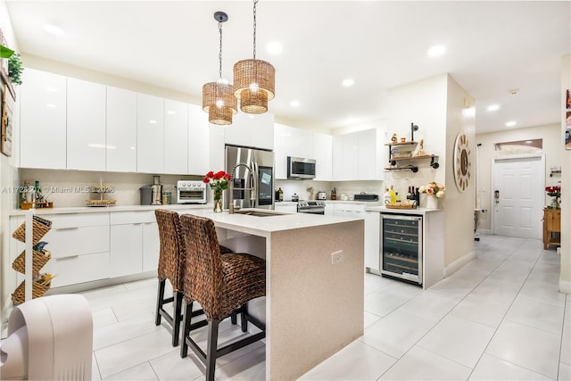 kitchen featuring pendant lighting, sink, white cabinets, wine cooler, and stainless steel appliances