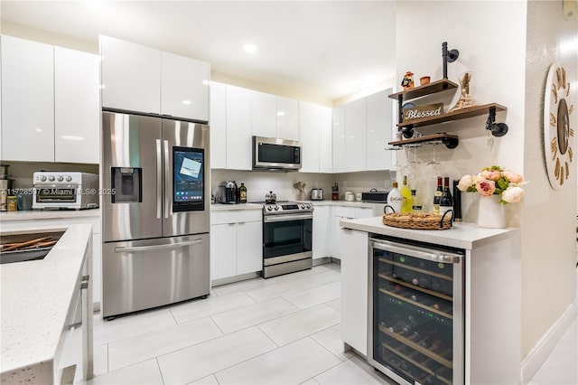 kitchen featuring wine cooler, white cabinetry, stainless steel appliances, light stone countertops, and decorative backsplash