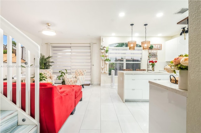 kitchen featuring pendant lighting, sink, white cabinets, and light tile patterned flooring