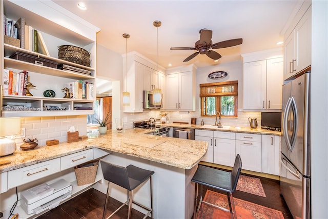 kitchen featuring white cabinetry, stainless steel appliances, a breakfast bar, and kitchen peninsula