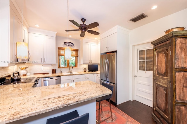 kitchen featuring white cabinetry, appliances with stainless steel finishes, sink, and a breakfast bar area