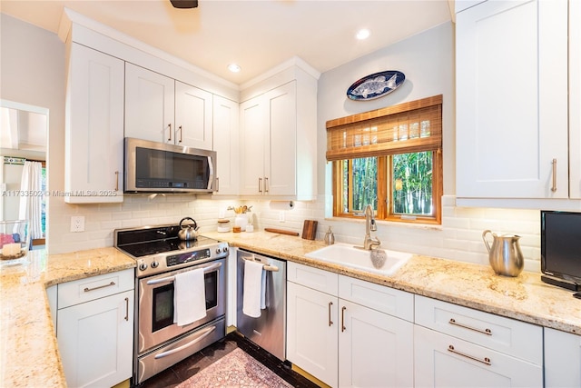 kitchen with white cabinetry, sink, light stone countertops, and appliances with stainless steel finishes