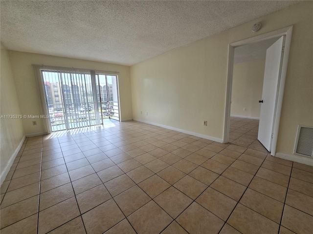 tiled empty room featuring a textured ceiling