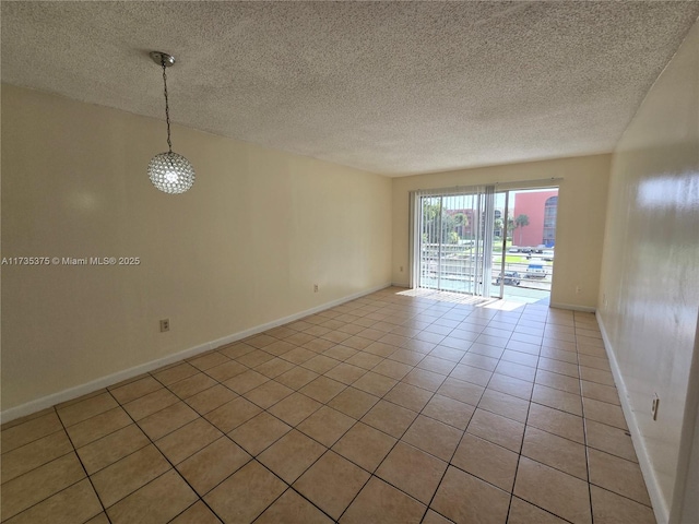 tiled empty room featuring a textured ceiling