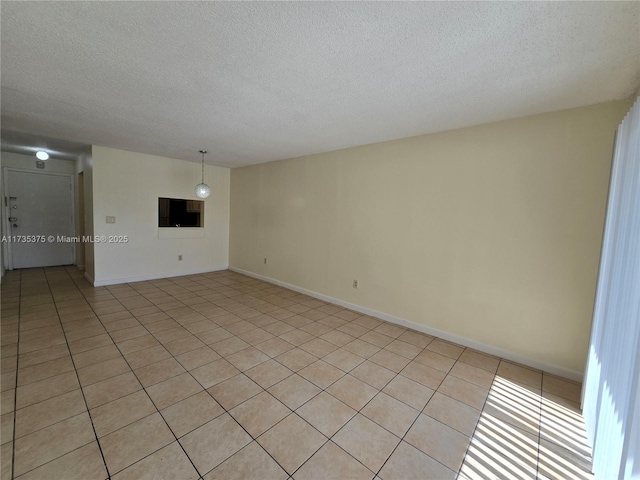 tiled empty room featuring a textured ceiling